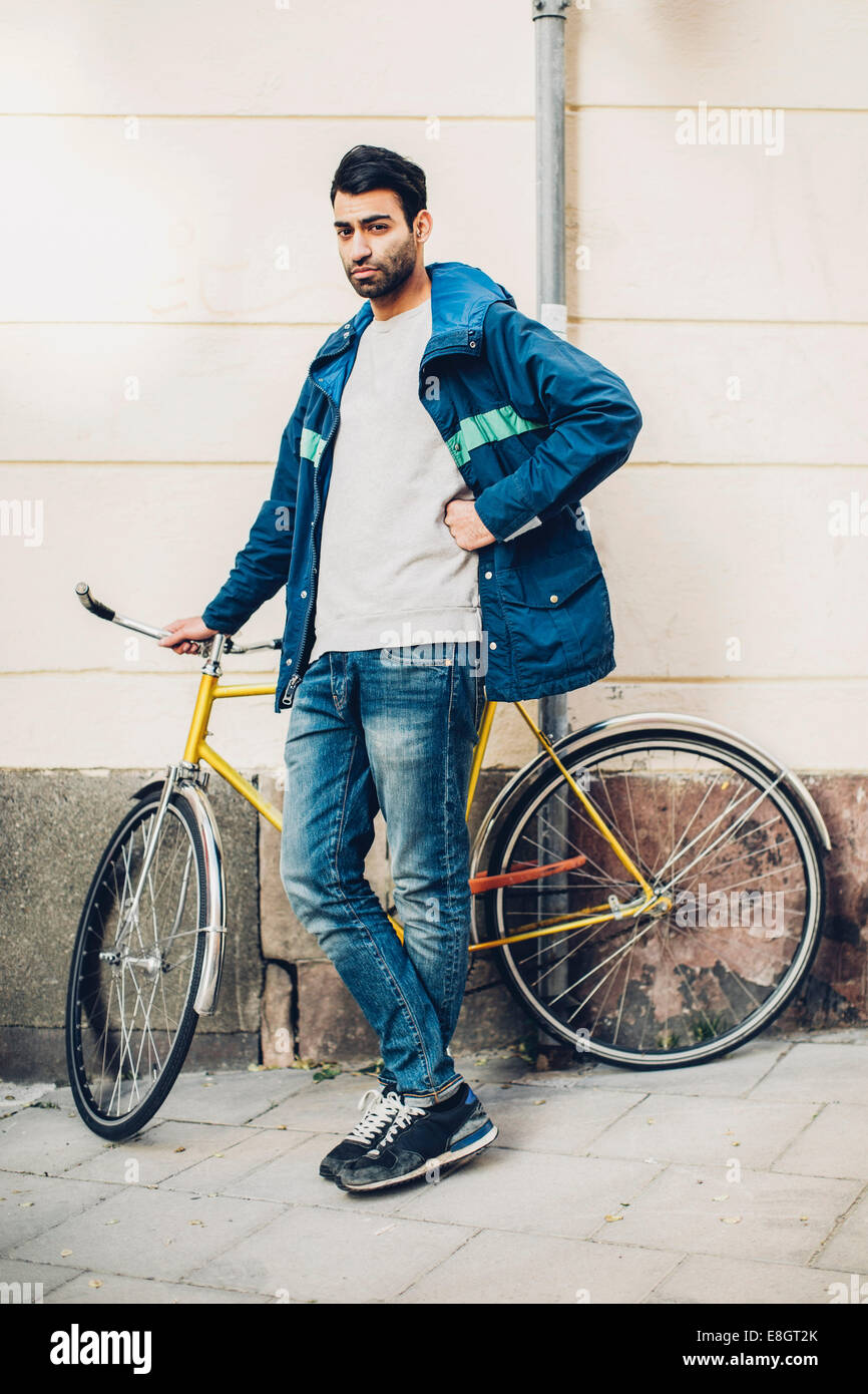 In voller Länge Portrait von zuversichtlich Mann mit Fahrrad auf Bürgersteig Stockfoto