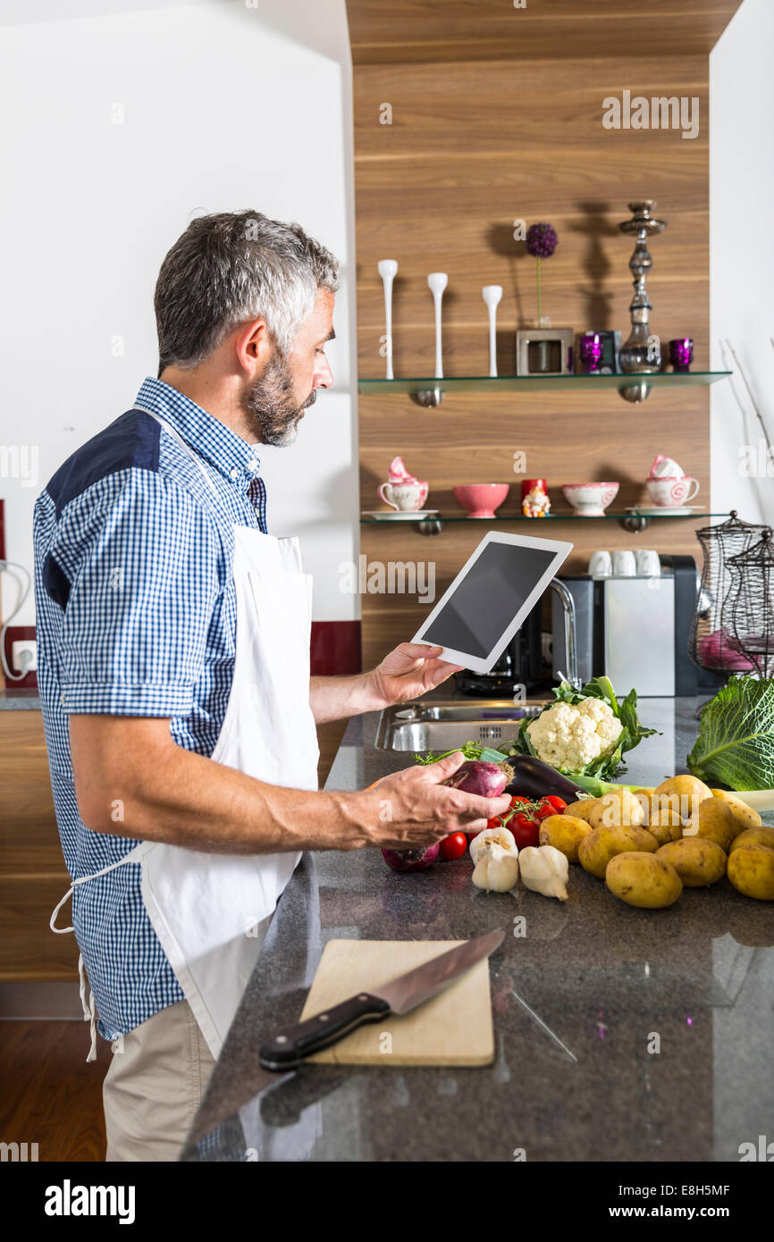 Österreich, Mann in der Küche mit Digital tablet Vorbereitung Essen Stockfoto