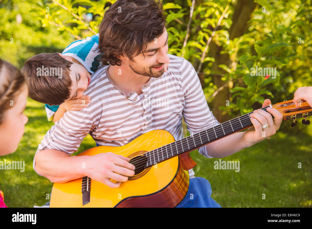 Vater mit Kindern Gitarre im Garten Stockfoto