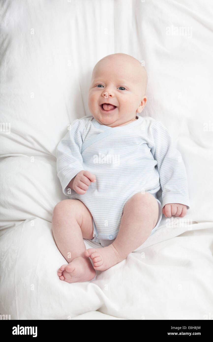 Deutschland, München, (2-5 Monate) Baby Boy auf Bett, lachen Stockfoto