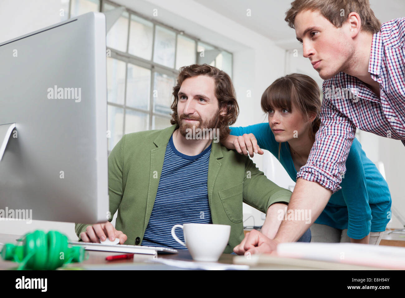 Drei Kollegen Blick auf Computer in einem kreativen Büro Stockfoto