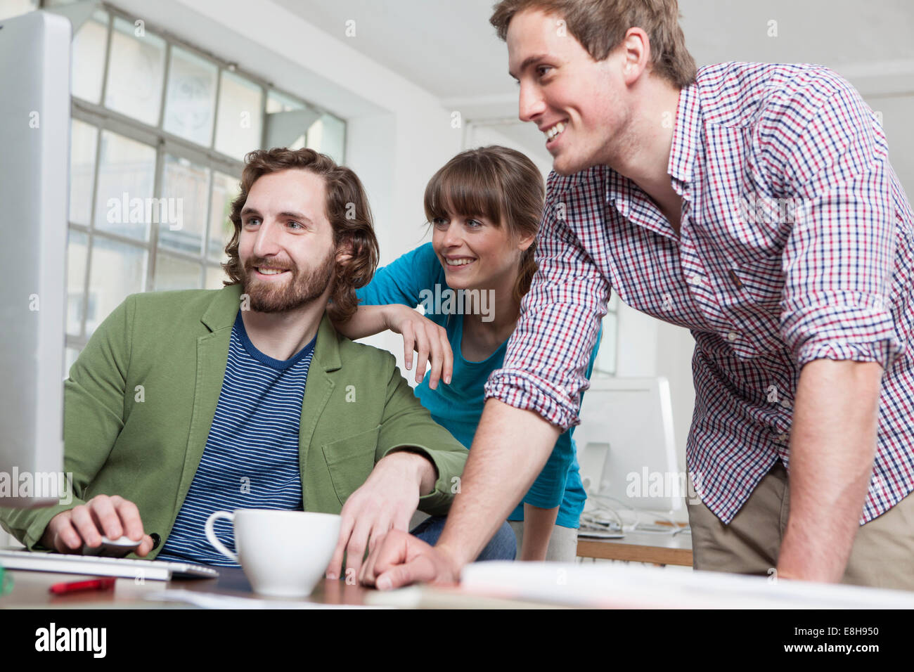Drei Kollegen Blick auf Computer in einem kreativen Büro Stockfoto