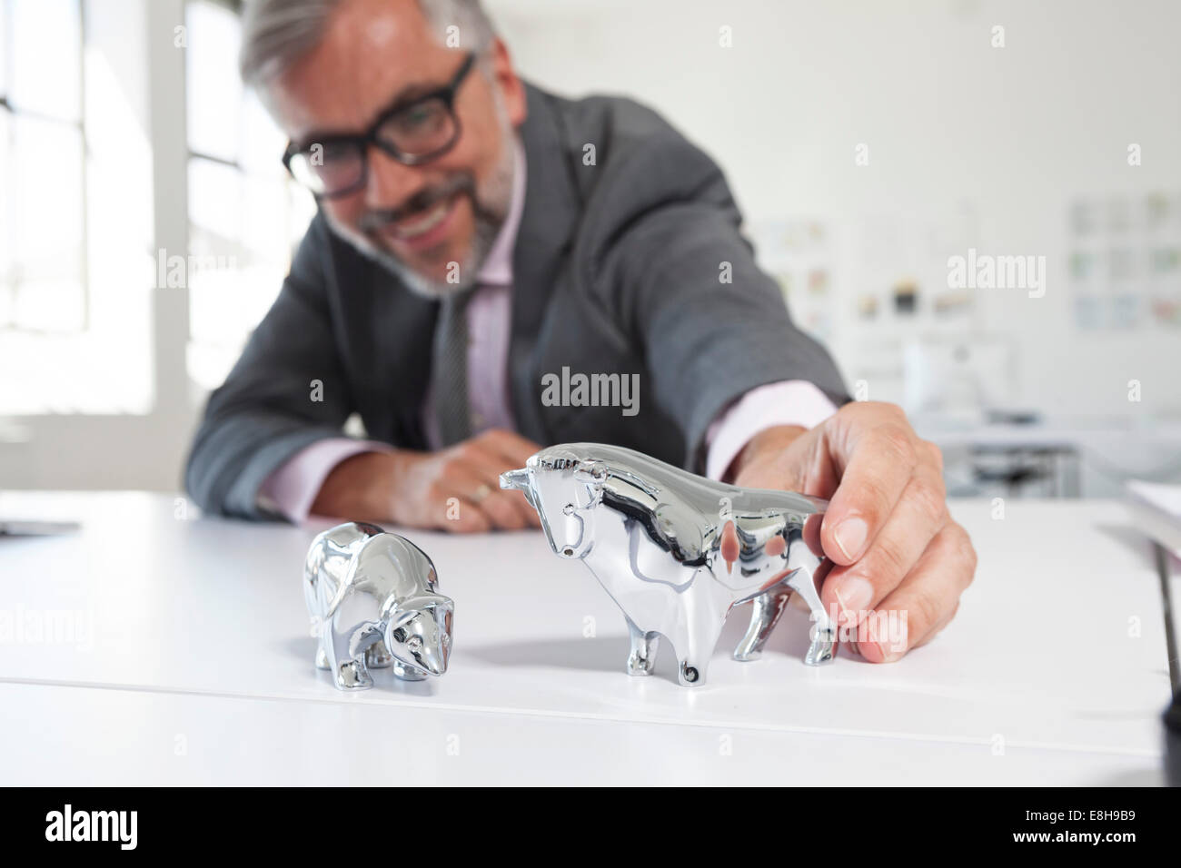 Geschäftsmann mit Bulle und Bär Figuren auf seinem Schreibtisch Stockfoto