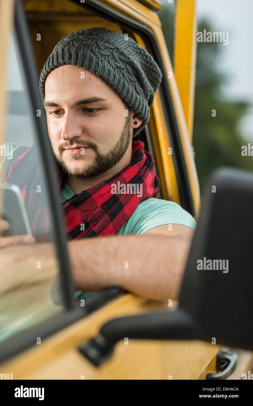 Junger Mann mit Handy sitzen in Pick-up-truck Stockfoto