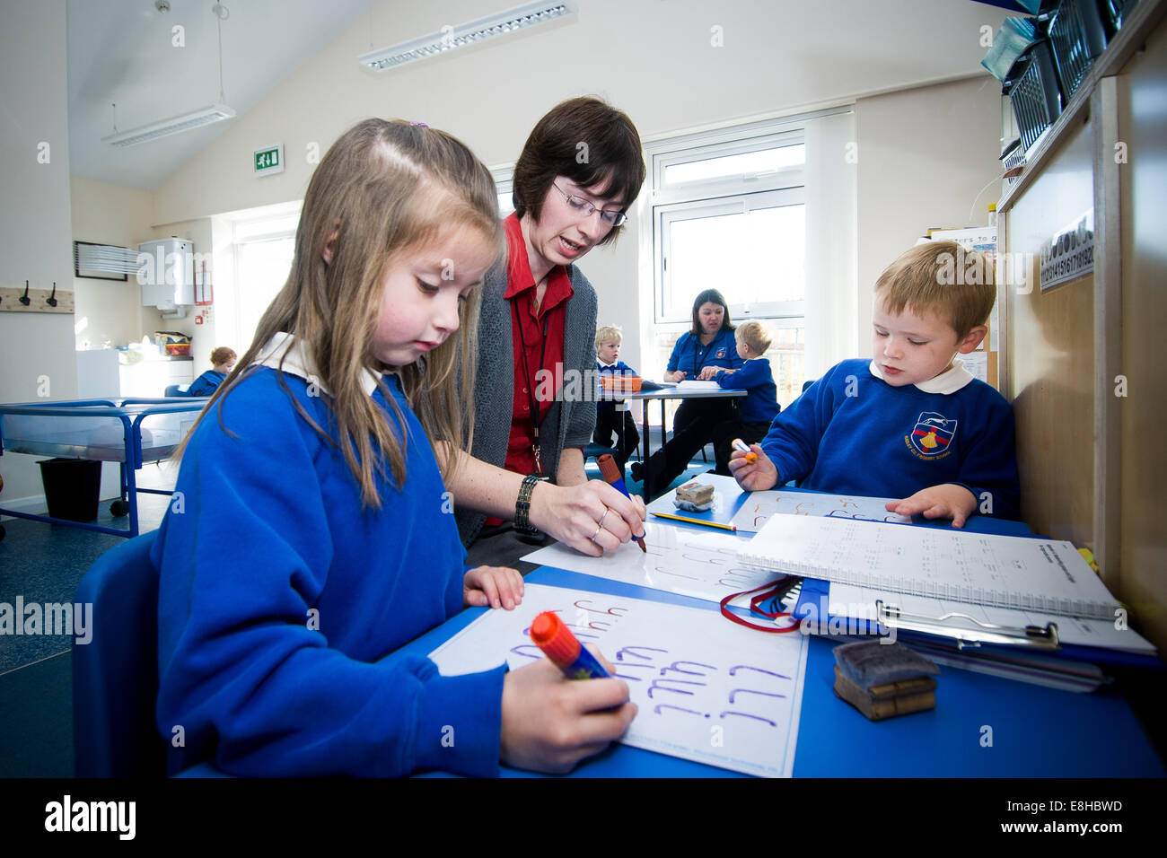 Kinder in der Vorschulklasse der Primary School in Großbritannien mit frühen Jahren Lehrer üben Alphabetisierung. Stockfoto