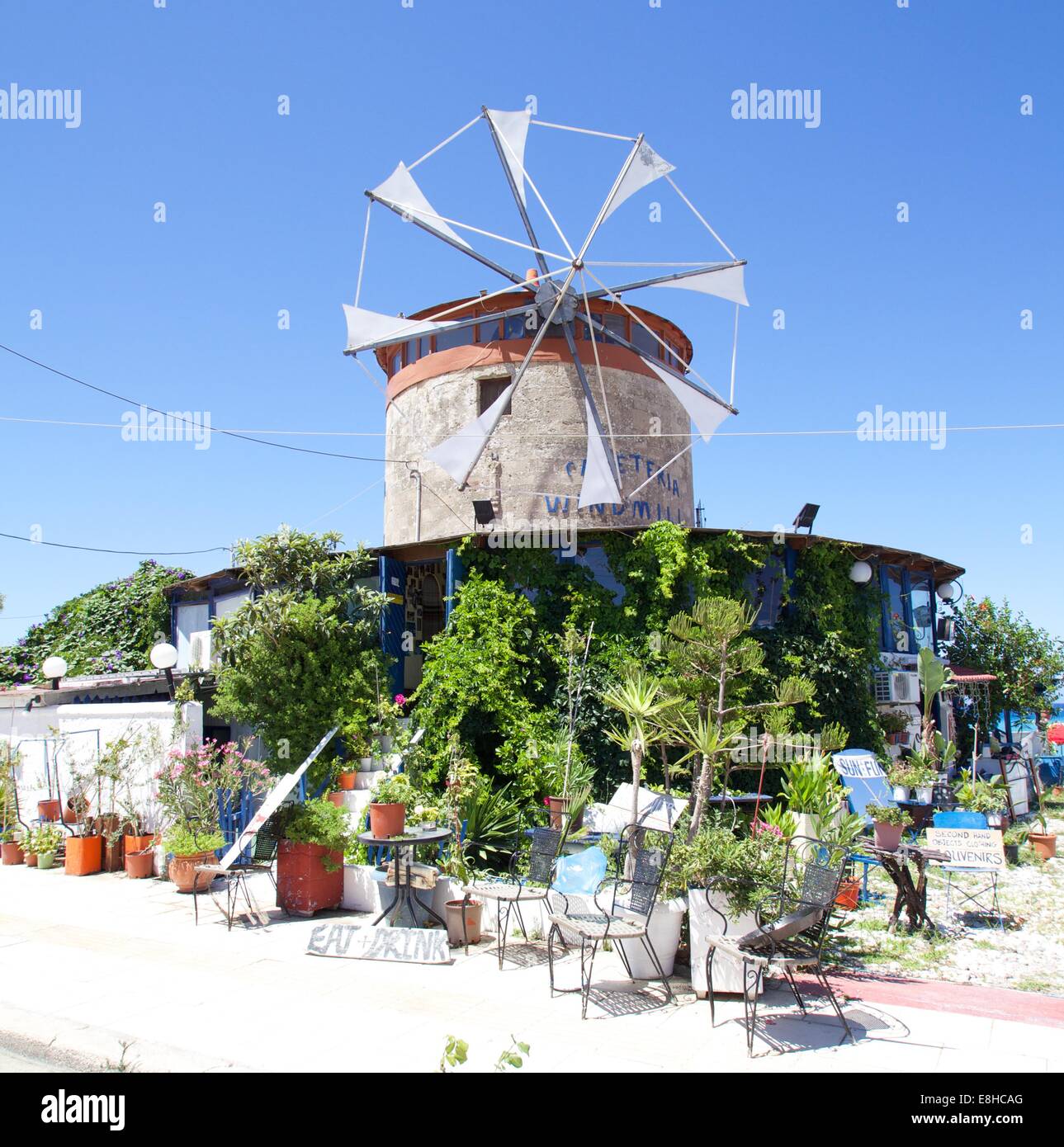 Eine alte Windmühle mit viel Grünpflanzen vor einem blauen Himmel als Hintergrund Stockfoto