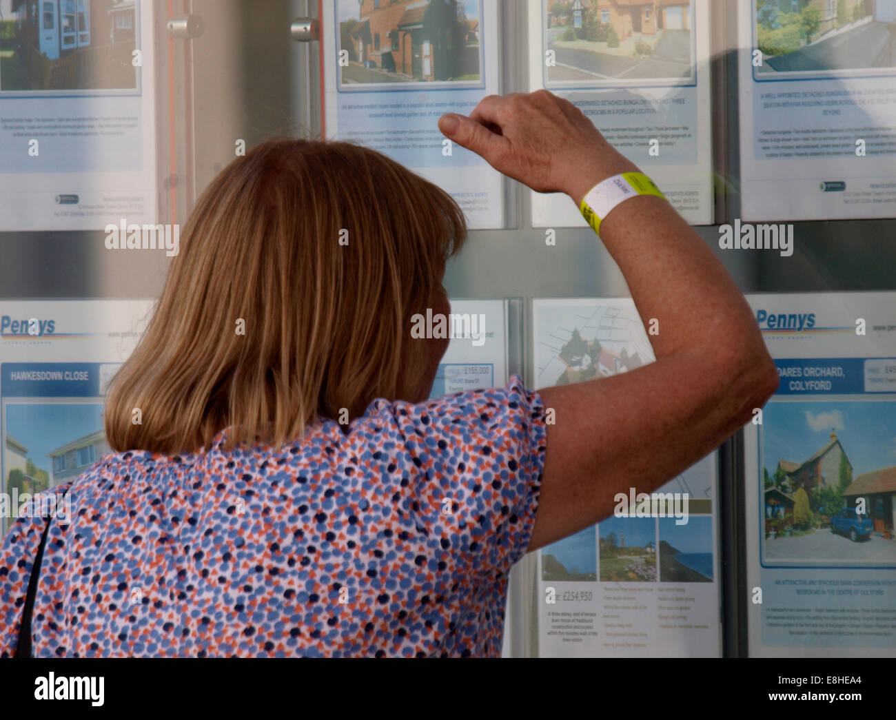 Frau auf der Suche in einem Immobilienmakler Fenster, Seaton, Devon, UK Stockfoto