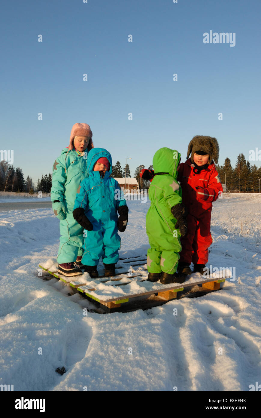 Kinder in bunten Winter Kleidung stehend auf einem ausrangierten Holzpalette Stockfoto
