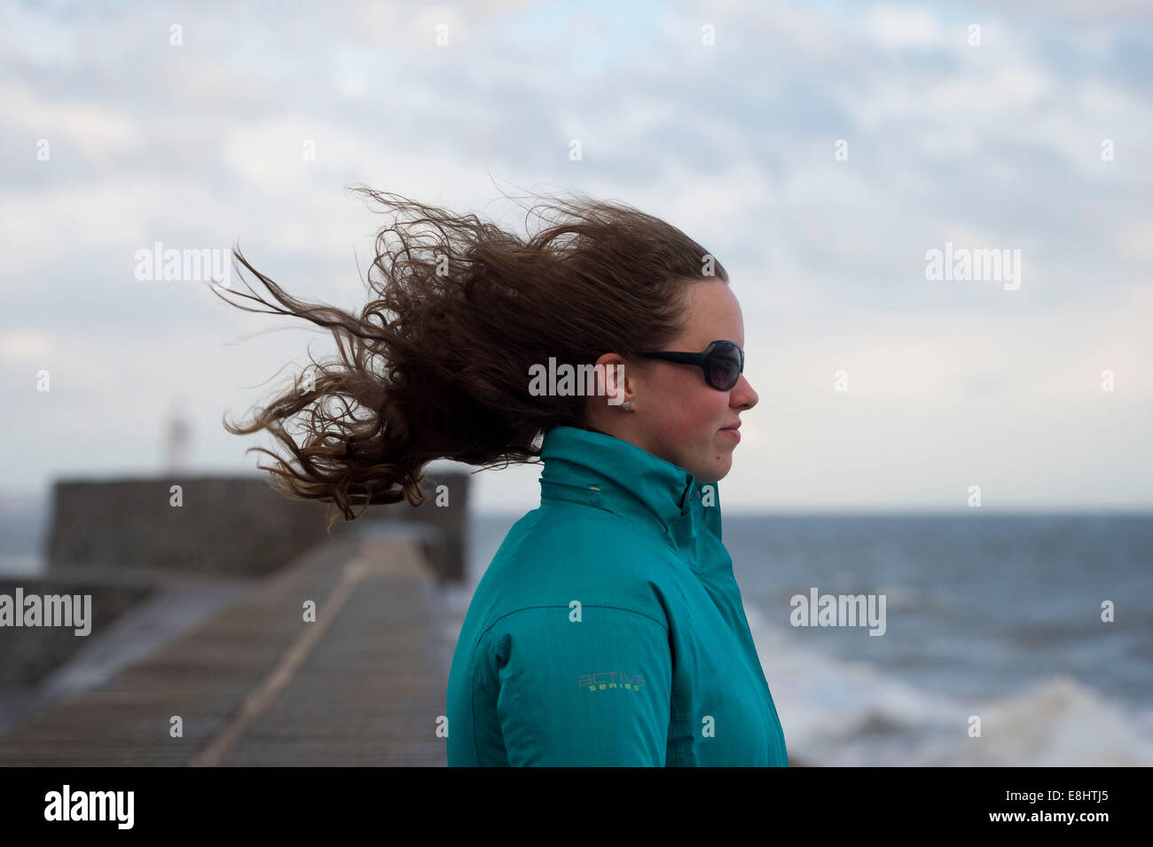 Ein junge weibliche Mädchen steht mit Blick in den Wind mit ihren Haaren weht hinter ihr. Stockfoto