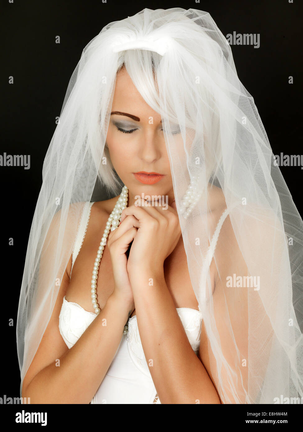 Junge Frau Braut zu sein eine weisse Hochzeit Schleier im Vorgriff auf ein neues Leben und ein Anfang in einer Lebenspartnerschaft vor einem schwarzen Hintergrund isoliert Stockfoto