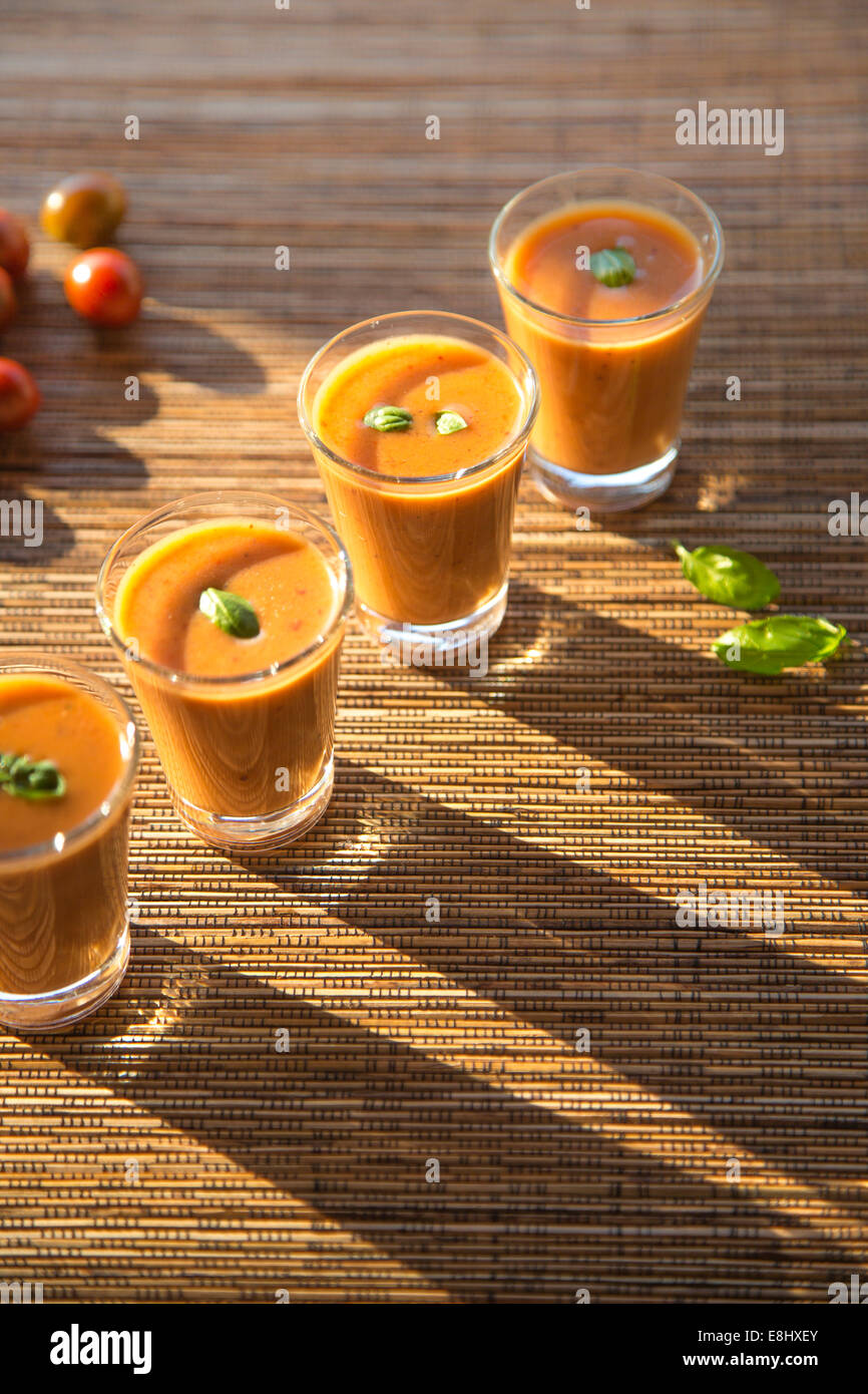 im Freien Schuss Tomaten Gazpacho oder Suppe in Gläsern mit Basilikum auf gewebte Bambusmatte Stockfoto