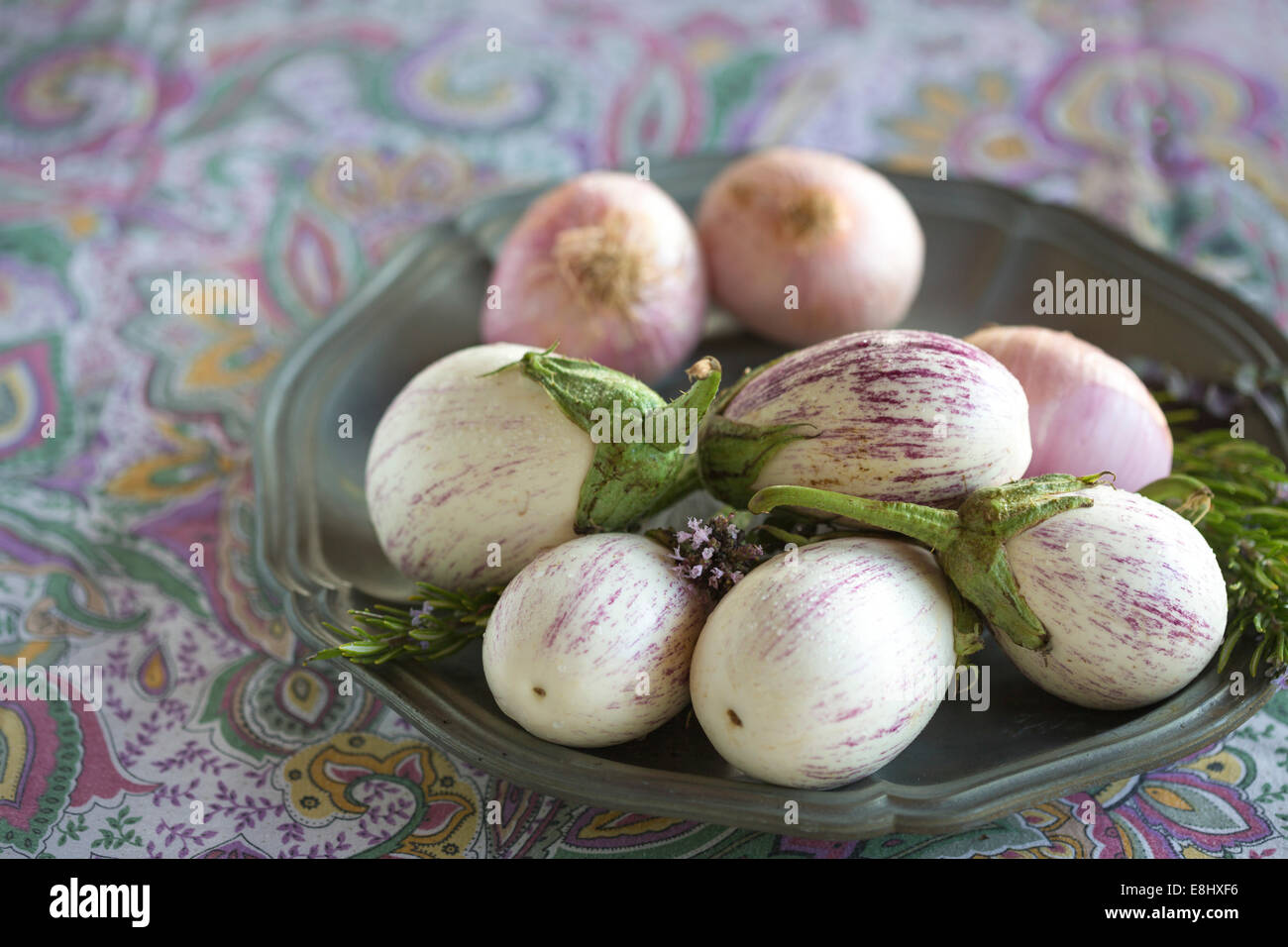 vergoldete weißen Auberginen mit lila feine Streifen und Zwiebeln gegen lila floral Tischdecke, Text-Raum, Stockfoto