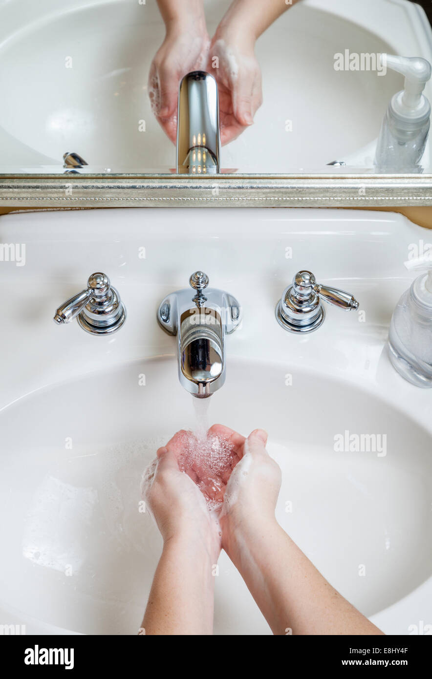 Frau wäscht Hände mit Seife in ein Waschbecken im Badezimmer Stockfoto