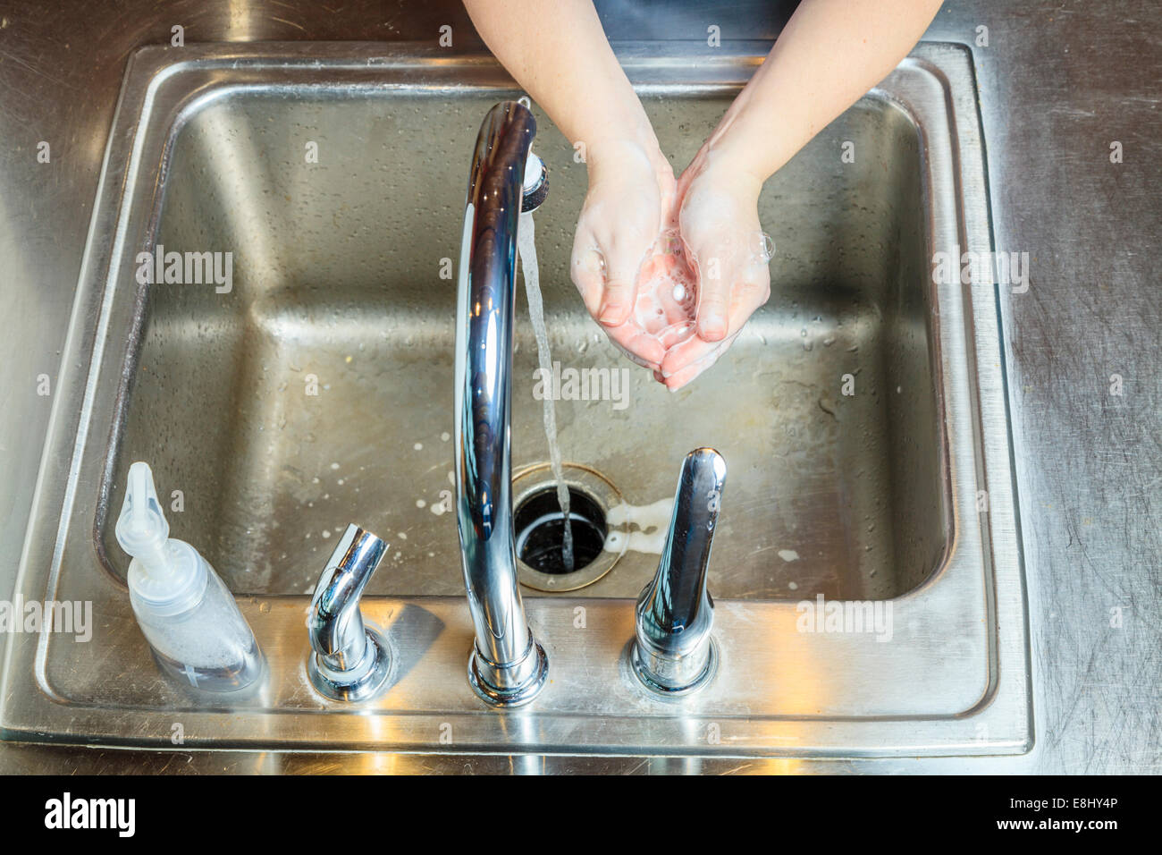 Frau wäscht Hände mit Seife in einer Küchenspüle Stockfoto