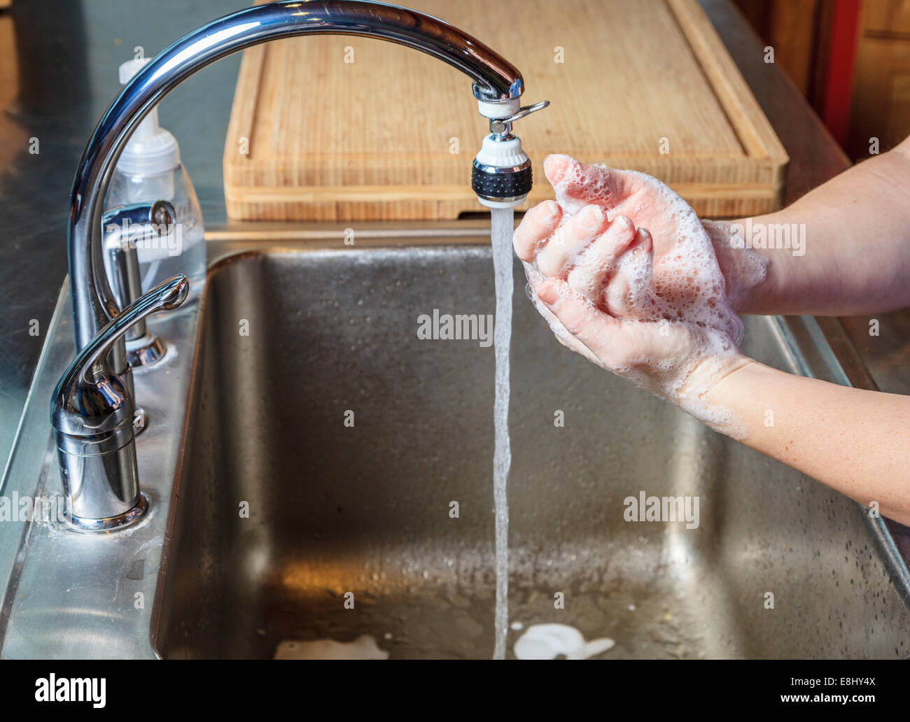 Frau wäscht Hände mit Seife in einer Küchenspüle Stockfoto