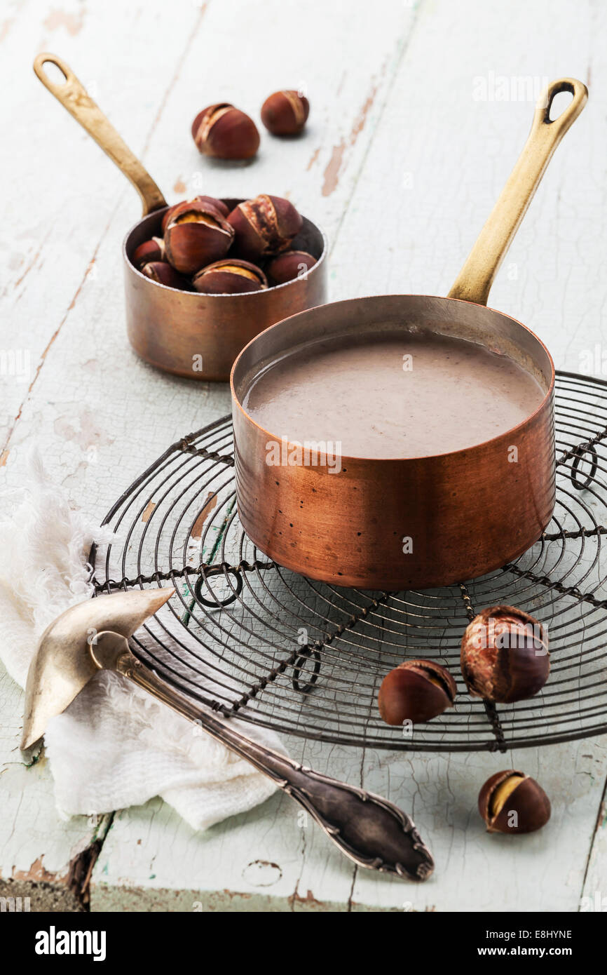 Kastaniensuppe im Kupferkessel mit gebratenen Kastanien auf blauem Hintergrund Textur Stockfoto