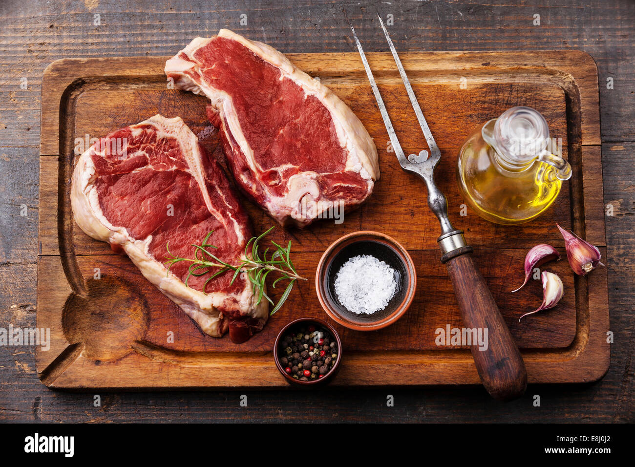 Rohes Frischfleisch Ribeye Steak, Würze und Fleischgabel auf dunklem Hintergrund Stockfoto