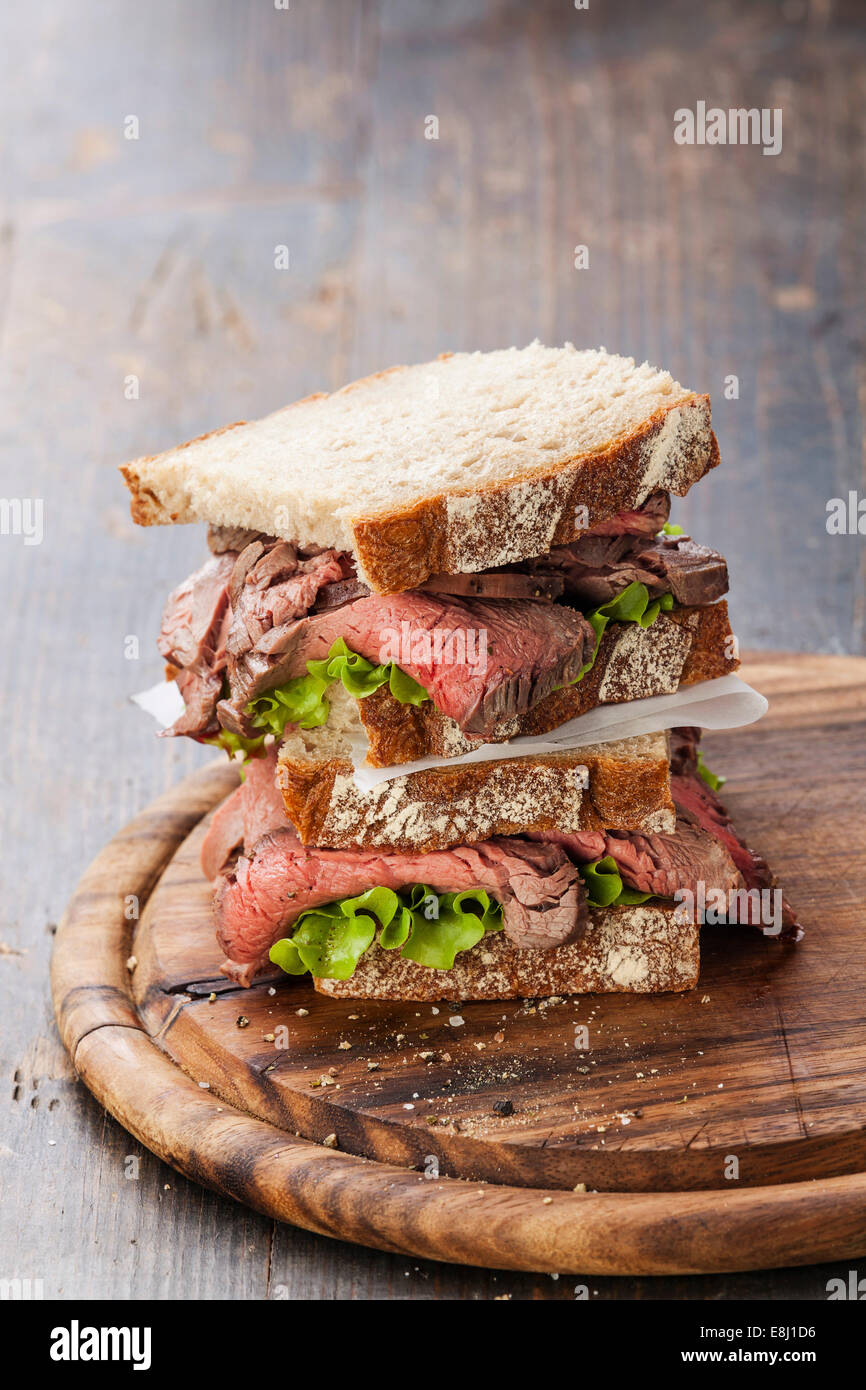 Roast Beef Sandwiches mit Salat auf Holzbrett auf dunklem Holz Stockfoto