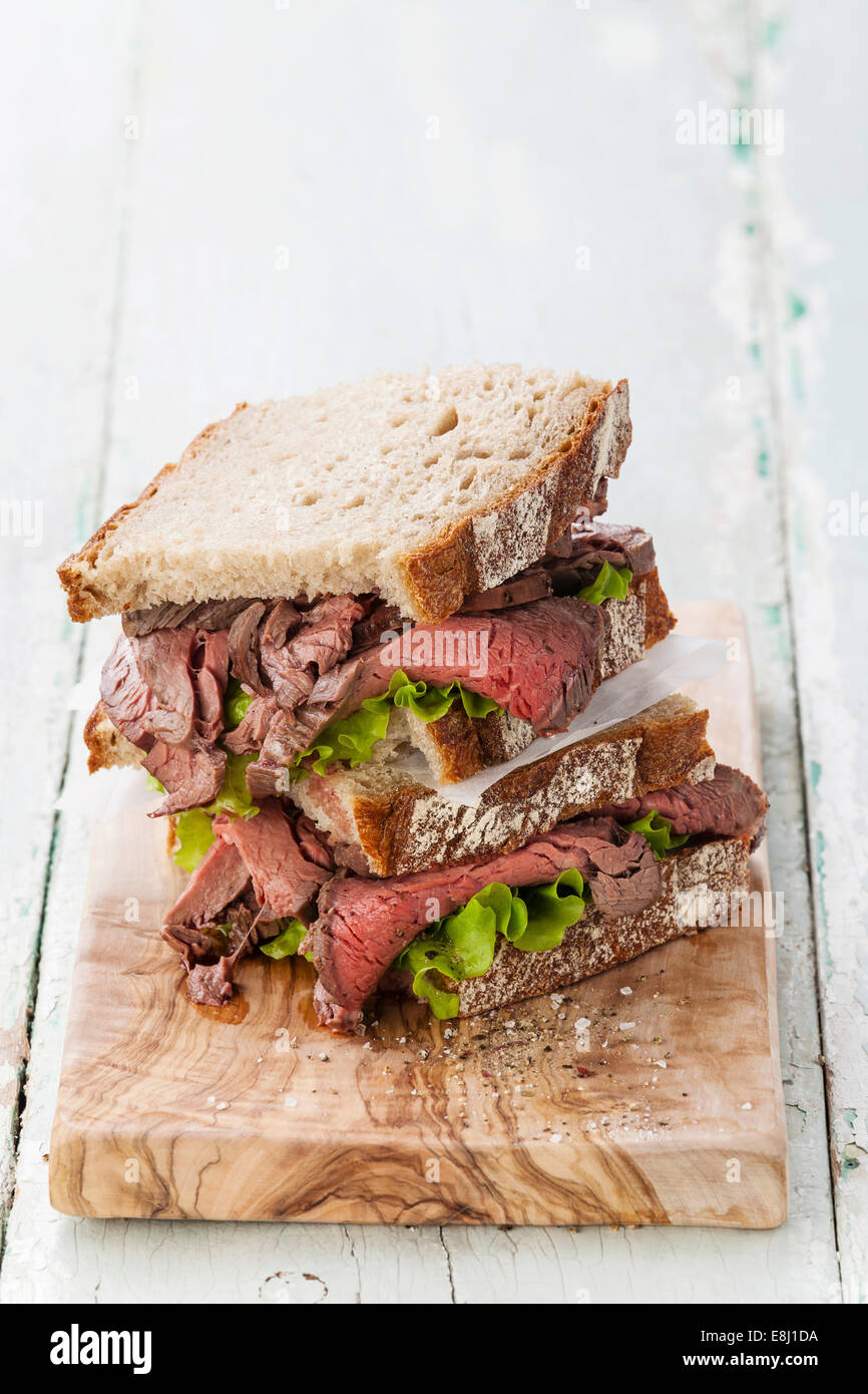 Roast Beef Sandwiches mit Salat auf Oliven Holz Schneidebrett Stockfoto