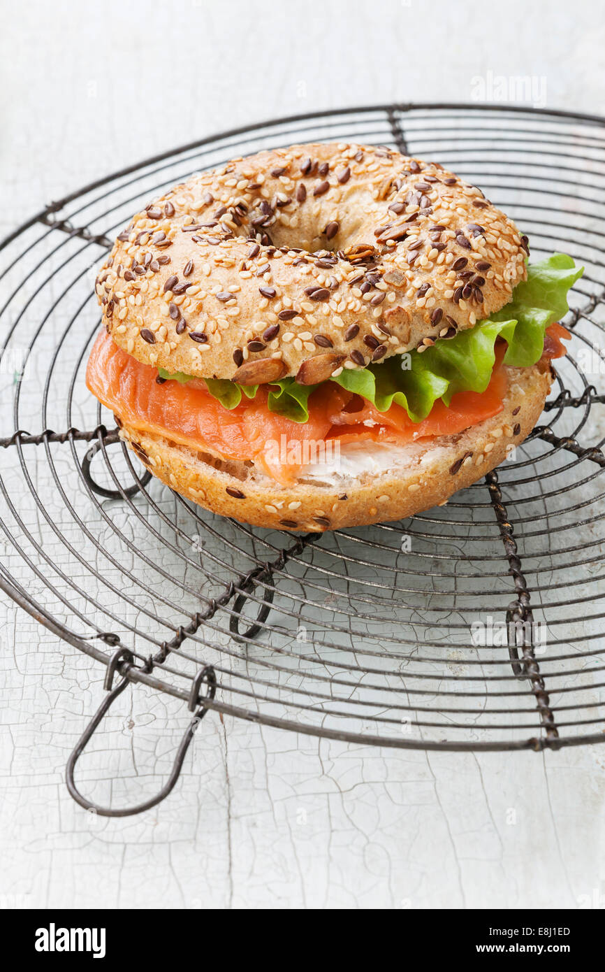 Lachs Bagel Sandwich mit Frischkäse und Korn auf blauem Hintergrund aus Holz Stockfoto