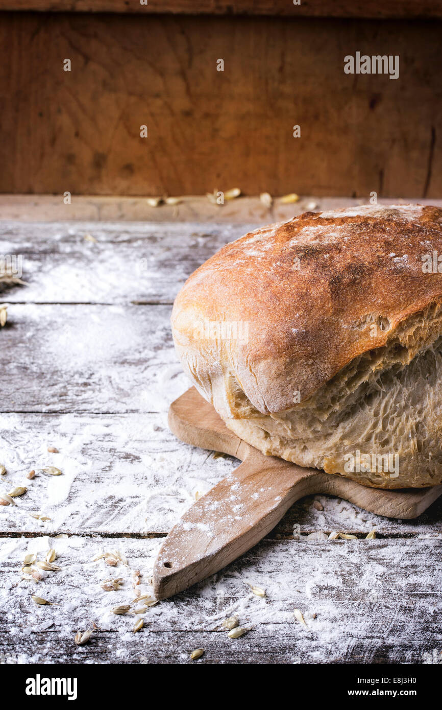 Frische hausgemachte Brot auf Holzbrett mit Vintage Messer diente über Holztisch mit Mehl. Serien ansehen Stockfoto