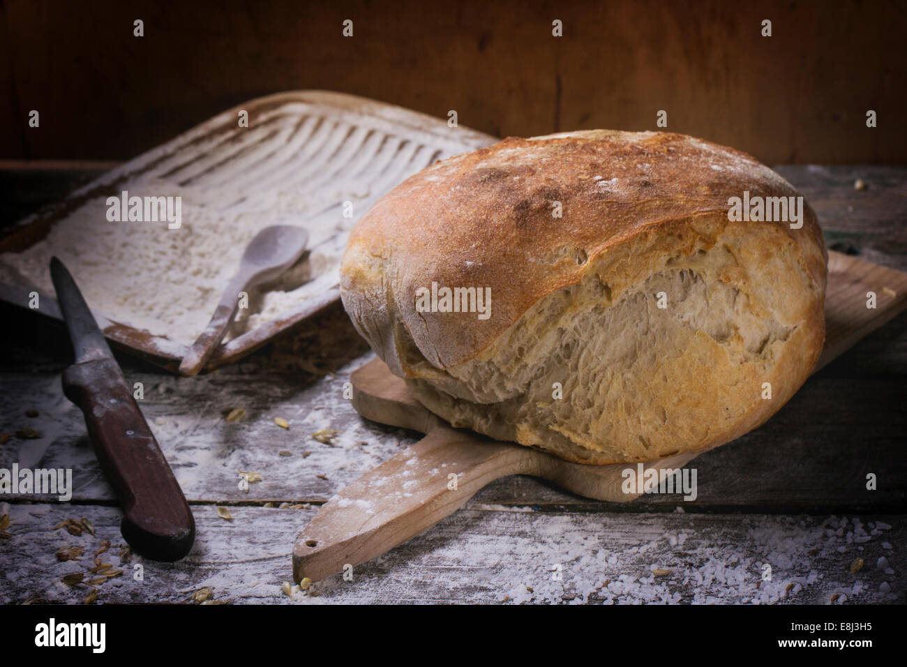 Frische hausgemachte Brot auf Holzbrett mit Vintage Messer diente über Holztisch mit Mehl Stockfoto
