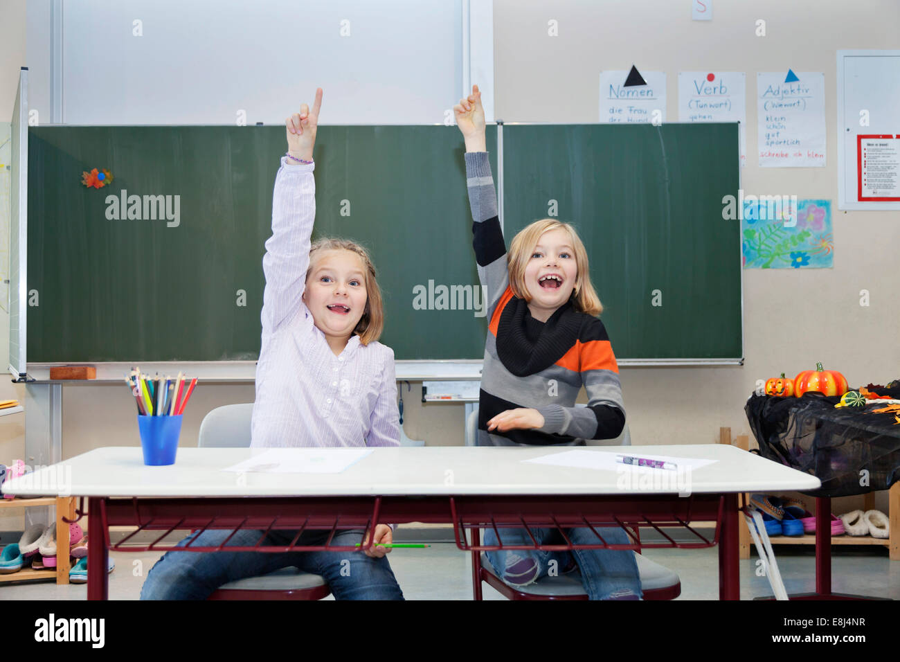 Zwei Schülerinnen, 7 und 9 Jahren, ihre Hände in der Klasse aufstellen Stockfoto