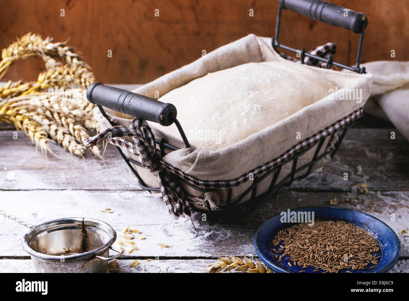 Brot backen. Teig in proofing Korb auf Holztisch mit Mehl, Kümmel und Weizen Ohren. Serien ansehen Stockfoto