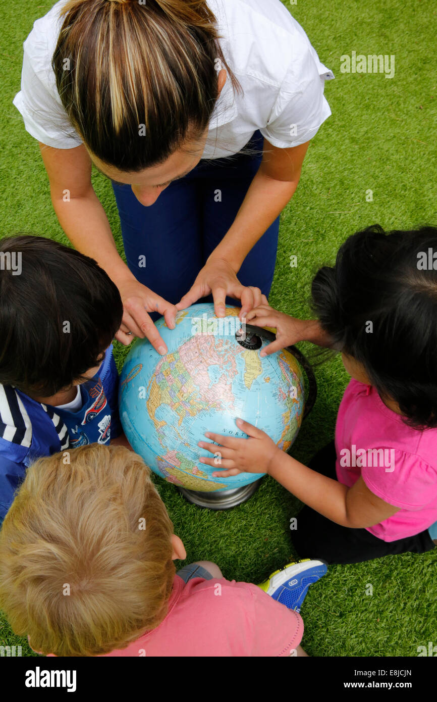Kindergärtnerin zeigt Länder auf einem Globus Stockfoto