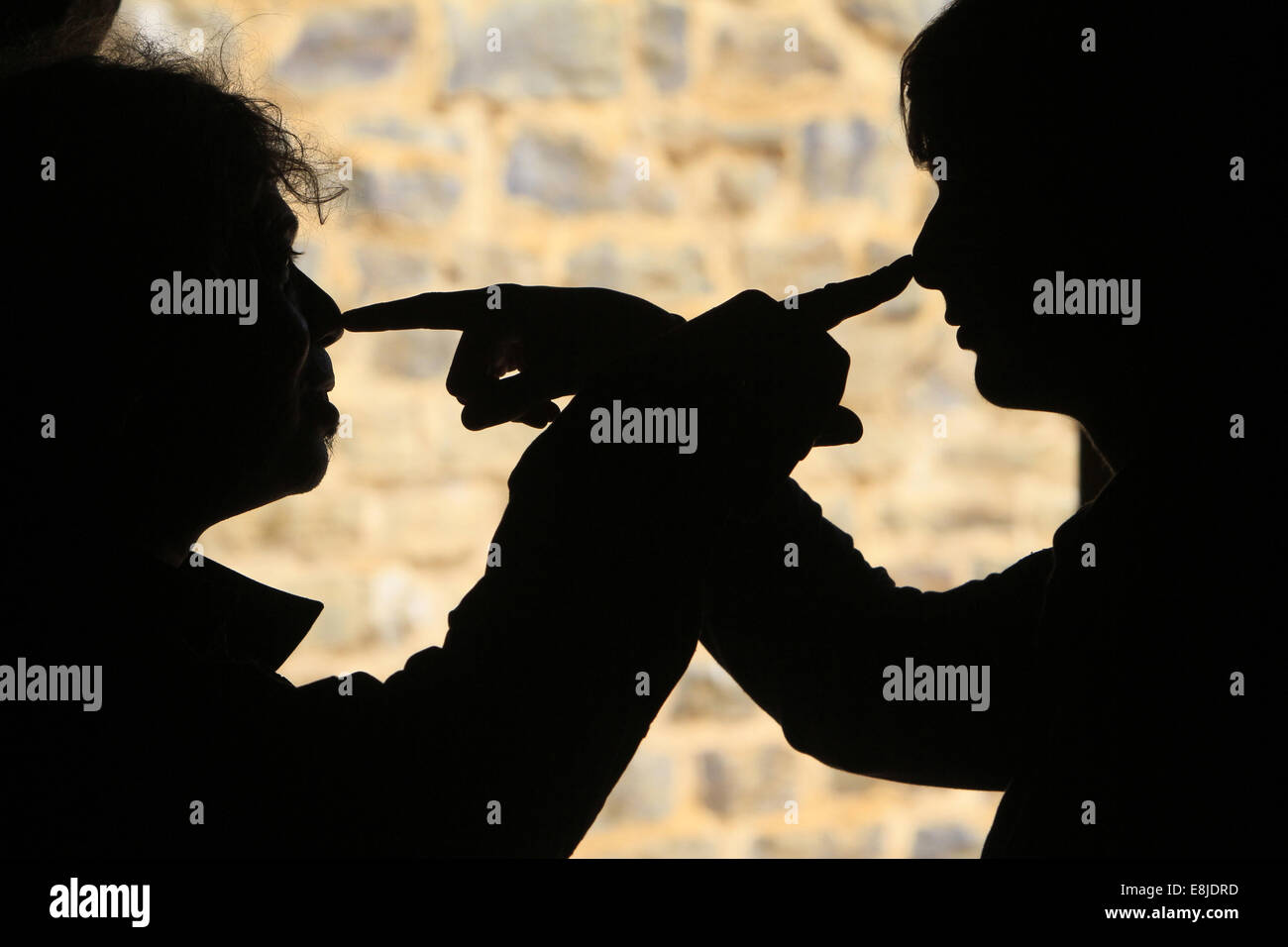 Silhouetten von zwei Männern berühren ihre Nase mit den Fingern. Stockfoto