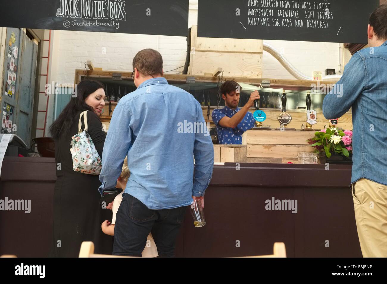 Eine Familie bestellt Getränke an die real Ale Stall Iin Altrincham Markthalle ["alkoholfreie Getränke für Kinder & Treiber verfügbar"] Stockfoto