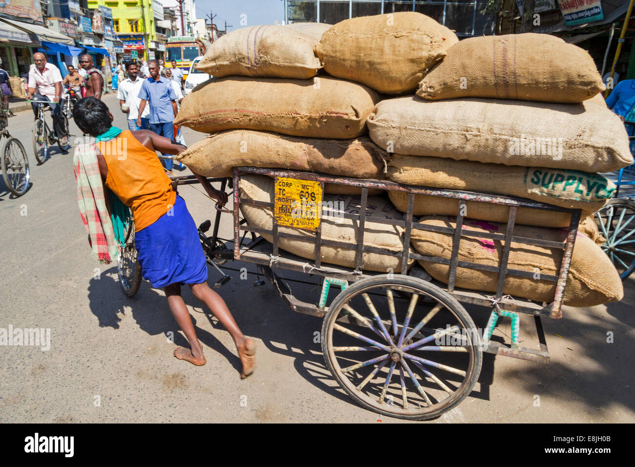 JUNGE RIKSCHA-FAHRER UND EINER BELASTUNG VON VIELEN SCHWEREN SÄCKE INDIEN Stockfoto