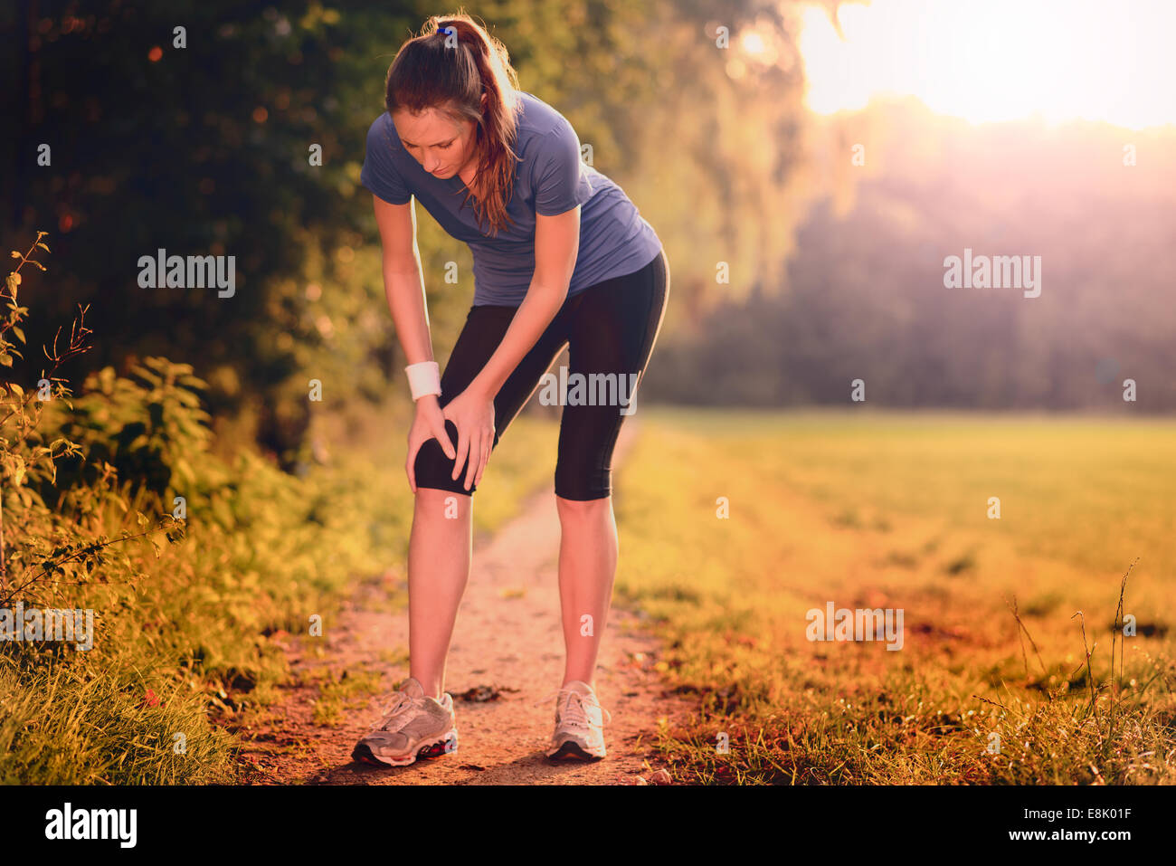 Junge Frau vor dem Training, Übungen Übungen, dehnen sie Muskeln auf einem Feldweg im Morgenlicht Stockfoto