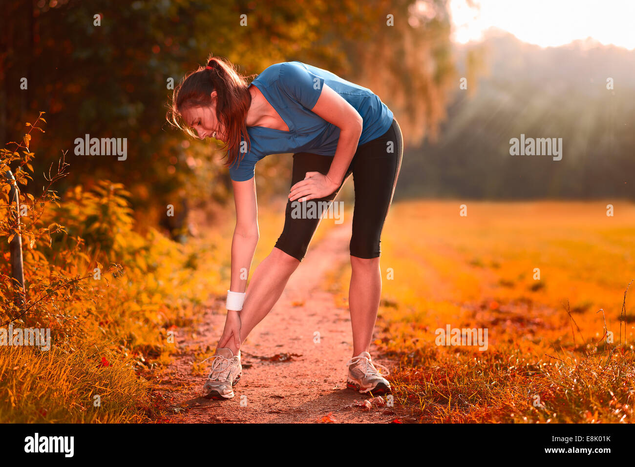 Junge Frau vor dem Training, Übungen Übungen, dehnen sie Muskeln auf einem Feldweg im Morgenlicht Stockfoto