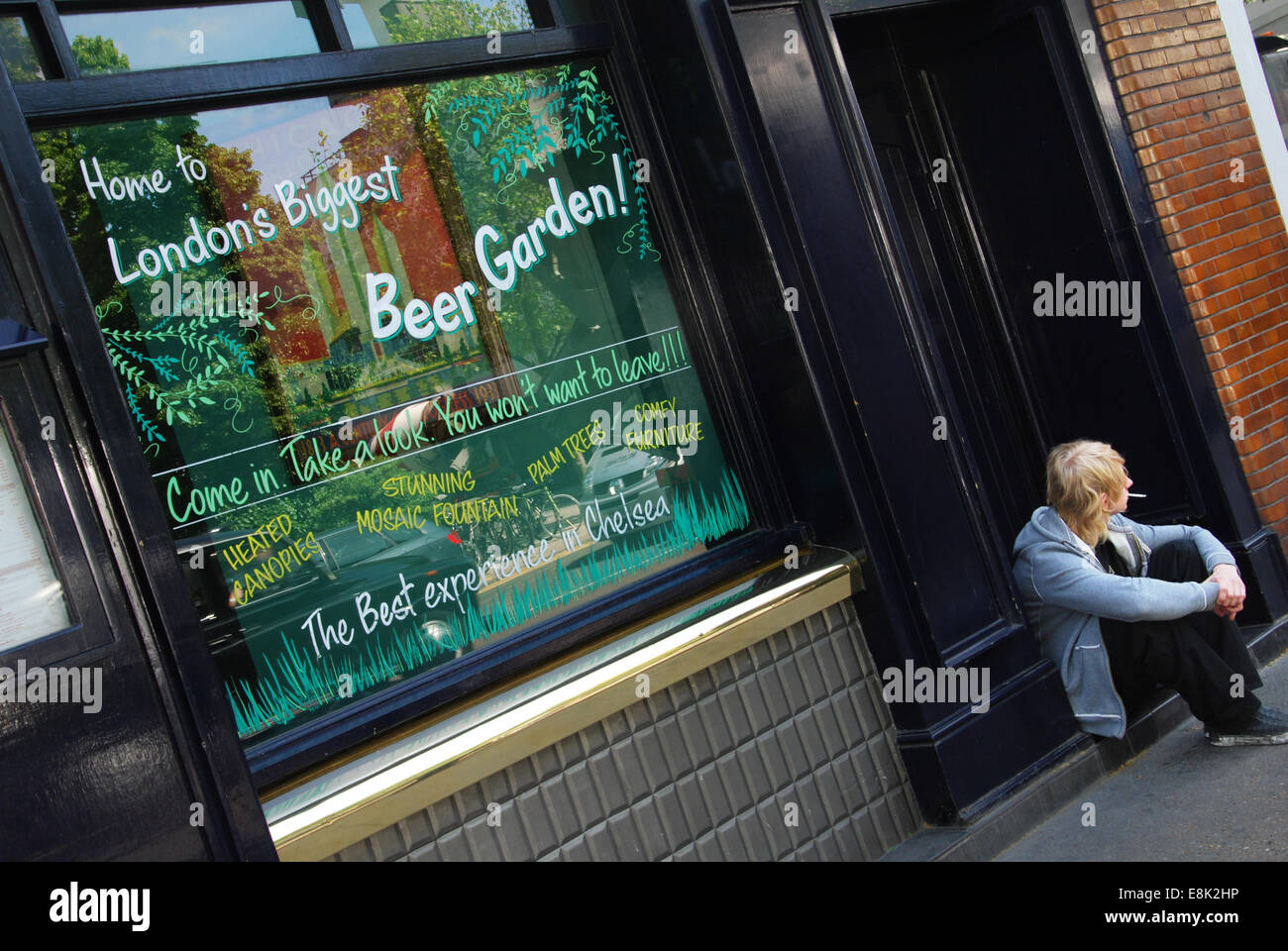 junger Mann sitzt vor London pub Stockfoto