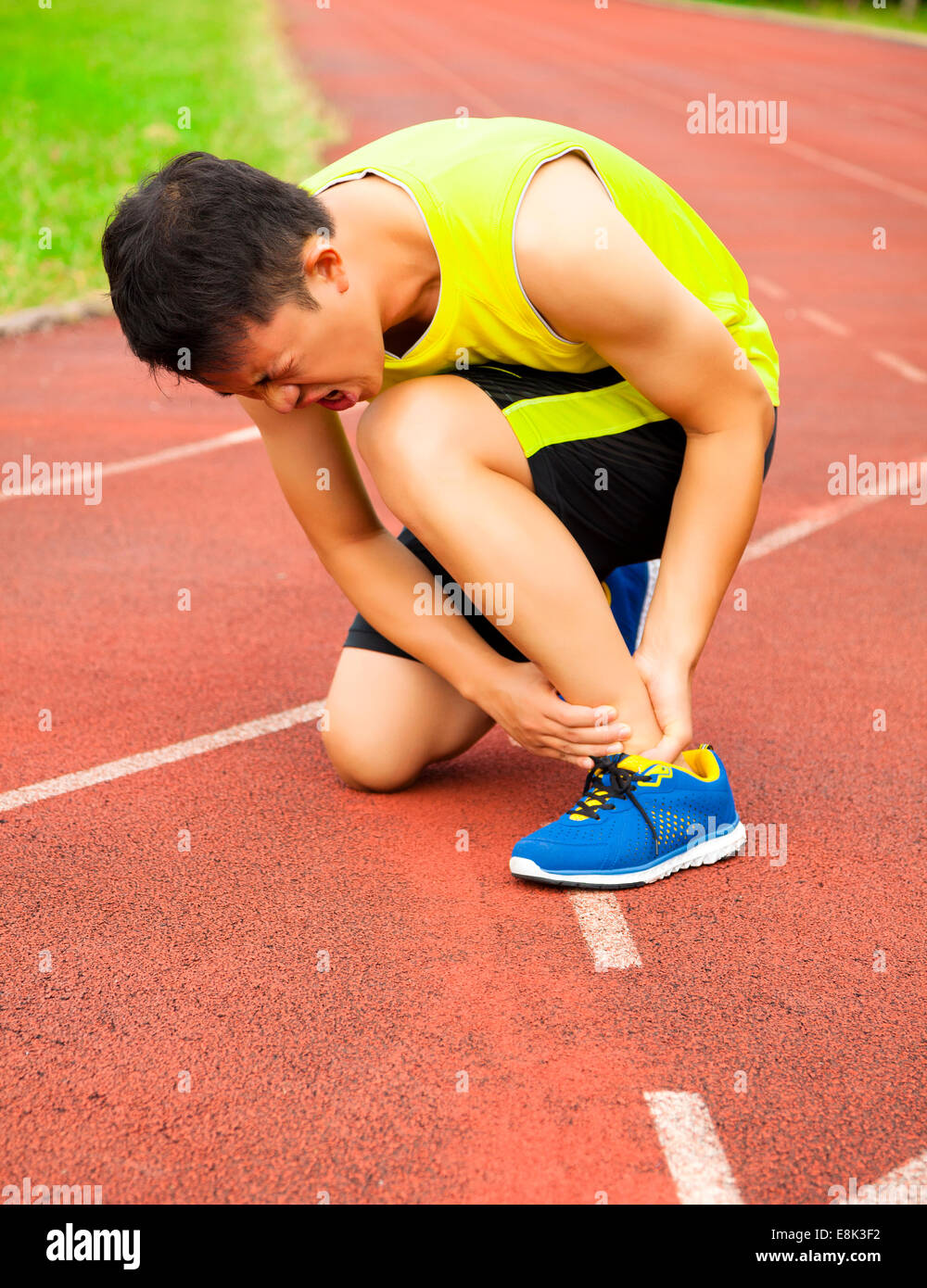 junge männliche Läufer mit Knöchelverletzung unterwegs im Stadion Stockfoto