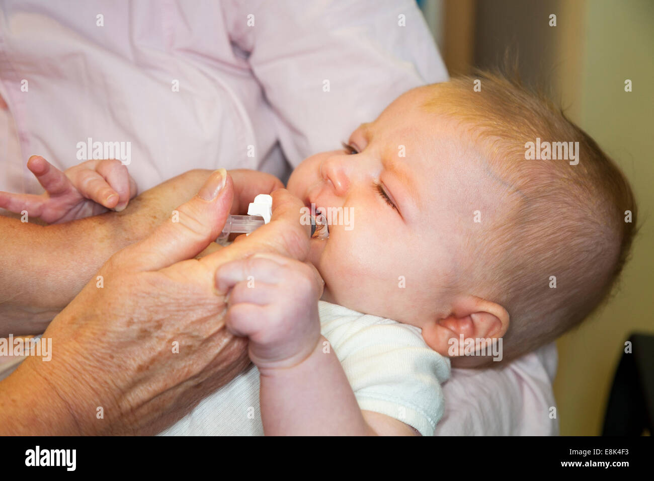 Mündliche Rota-Virus / Rotavirus-Impfung / Impfung vom Spritze in Mund von 12 13 / zwölf / dreizehn Wochen alten Baby + Mutter Stockfoto