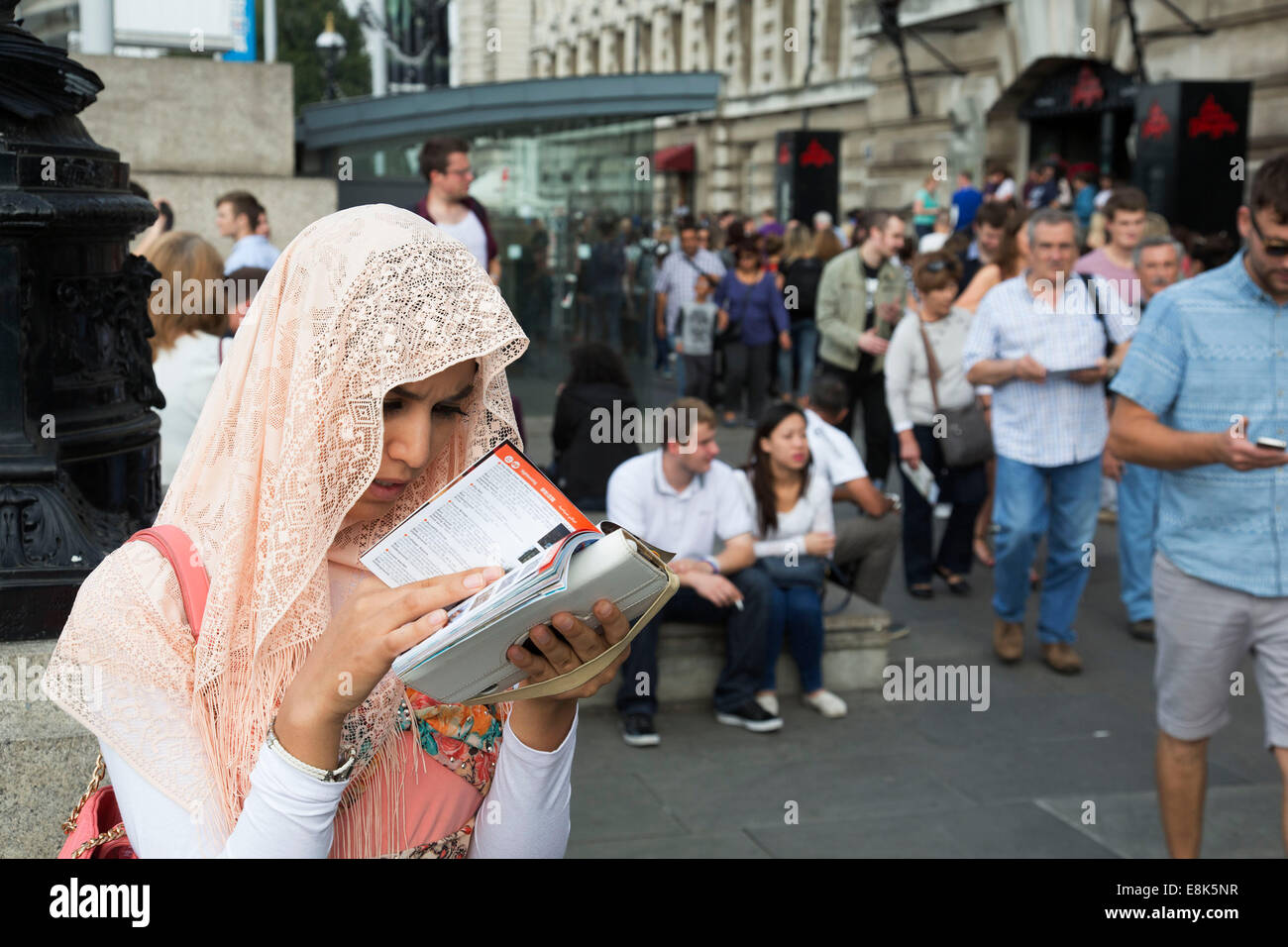 Eine asiatische Frau Tourist ein Pfirsich farbigen Kopftuch schaut auf ihre Karte, um herauszufinden, welcher Weg zu gehen. South Bank, London, UK Stockfoto