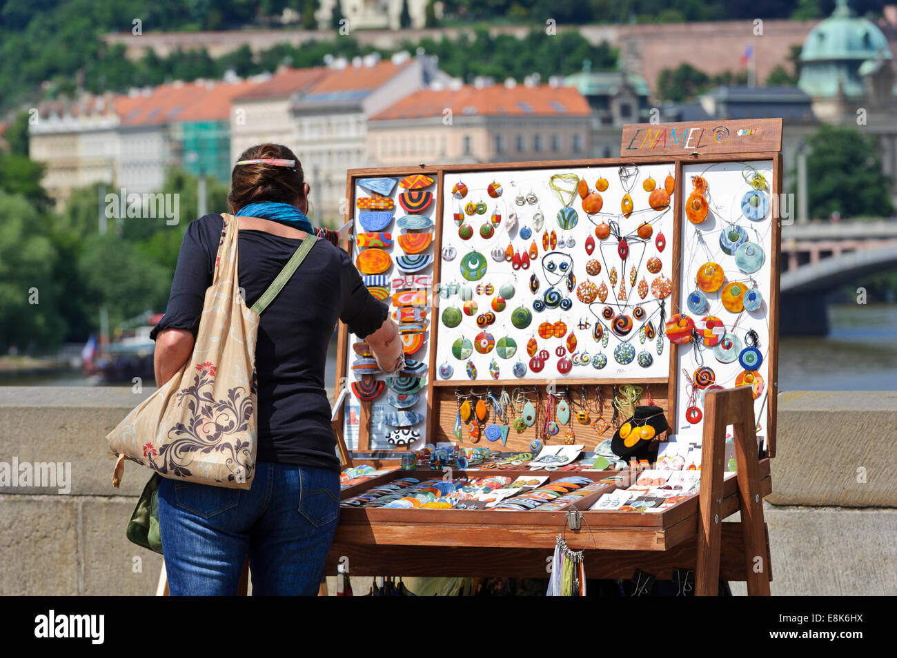 Eine Frau berühren einen kleinen Gegenstand aus einem Stall zu verkaufen Schmuck auf der Karlsbrücke, Prag, Tschechische Republik. Stockfoto