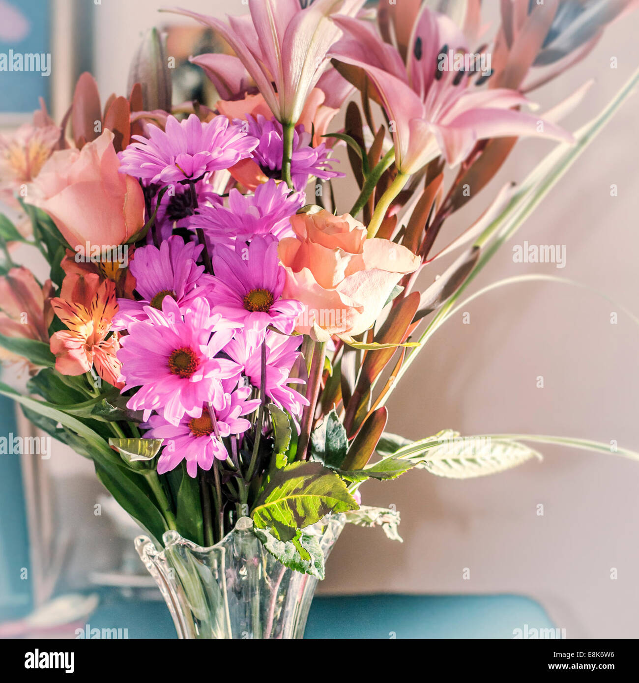 Nahaufnahme der Anordnung der lila, rosa & blass orange Blumen in einer Vase Klarglas. Stockfoto