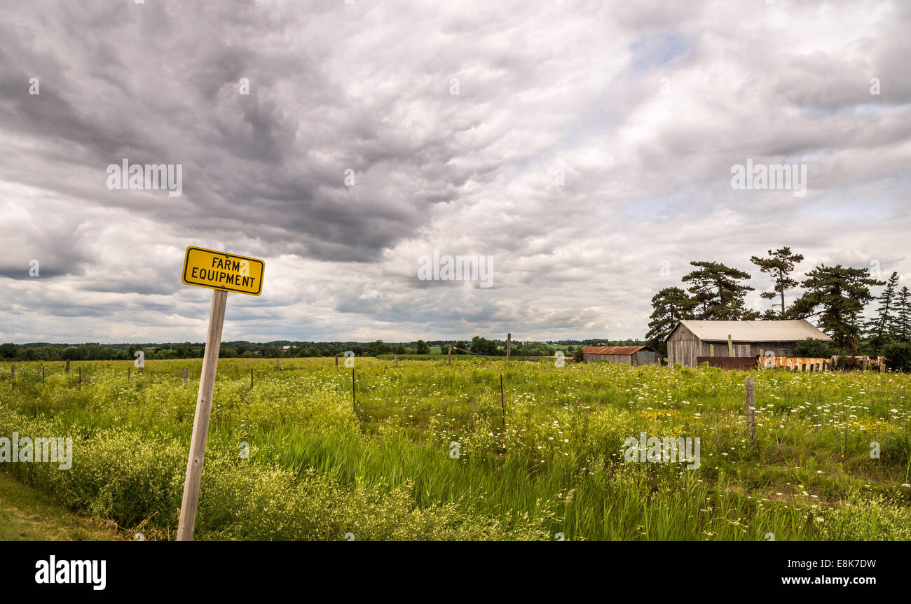 Einen dramatischen Himmel über Farm Equipment Zeichen und Scheune. Stockfoto