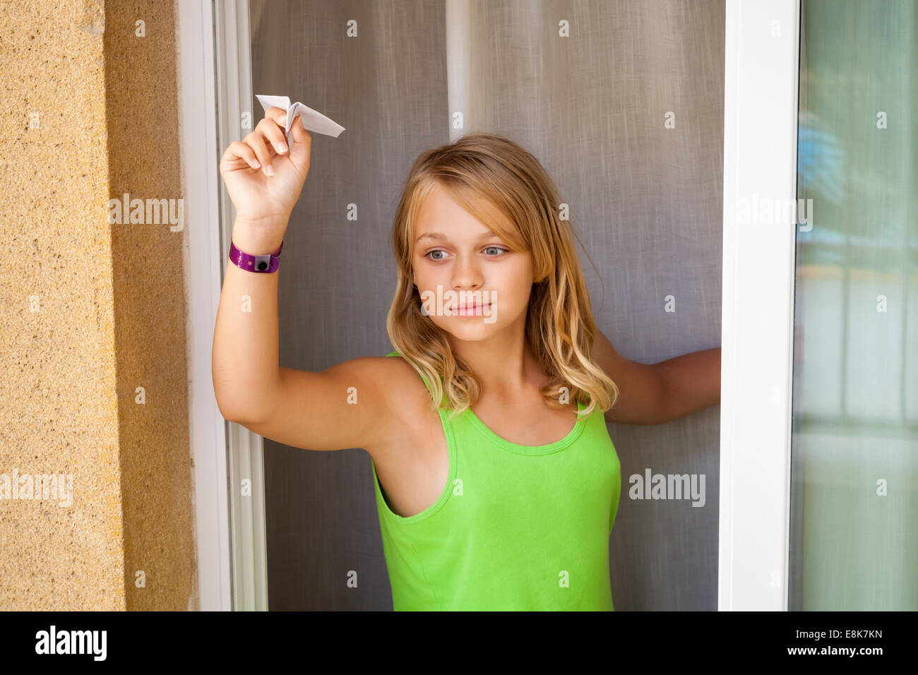 Kleine blonde kaukasische Mädchen mit kleine Papierflieger im Fenster "" Outdoor-close-up portrait Stockfoto