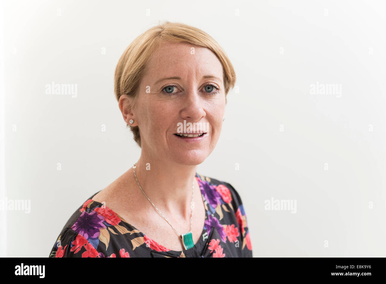 Kopf und Schultern Kopf geschossen Porträt einer Frau mit kurzen Haaren gegen eine schlichte weiße Wand. Stockfoto