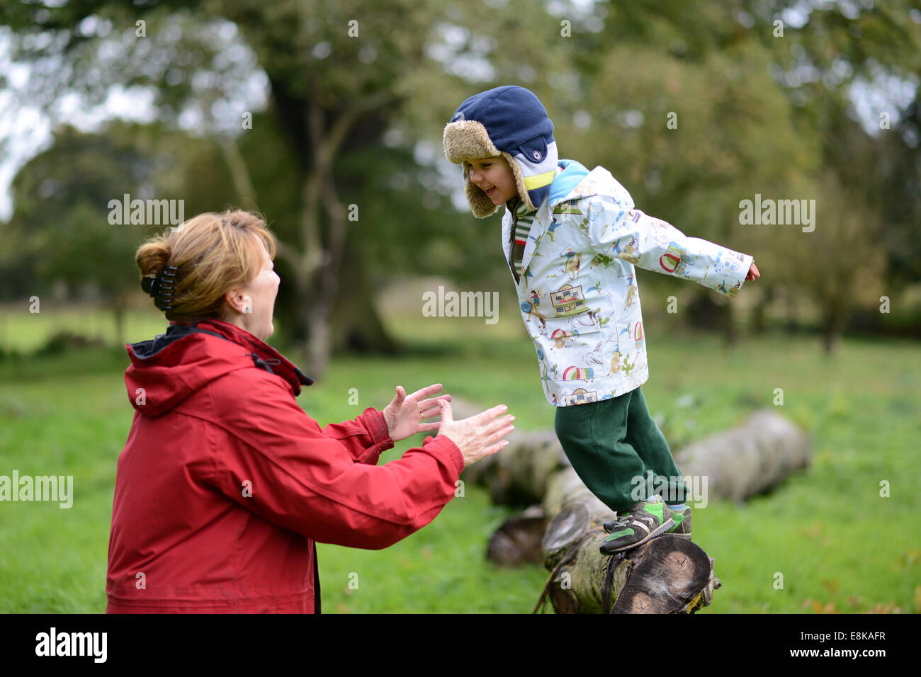 Kind Kinder junge Outdoor-Spaß mit Oma in die Arme springen trust vertrauensvolle Uk Stockfoto