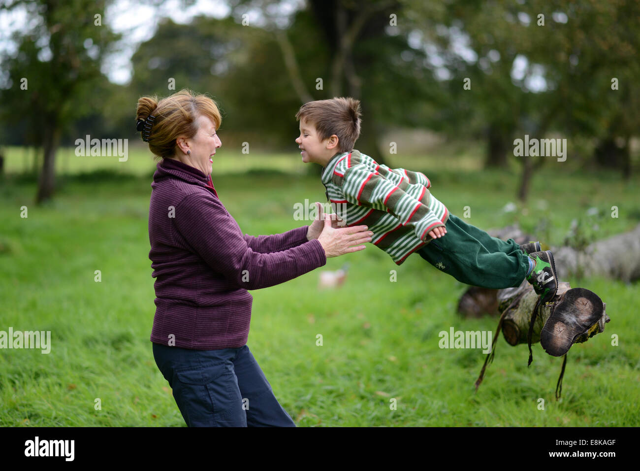 Kind Kinder junge Outdoor-Spaß mit Oma in die Arme springen trust vertrauensvolle Uk Stockfoto