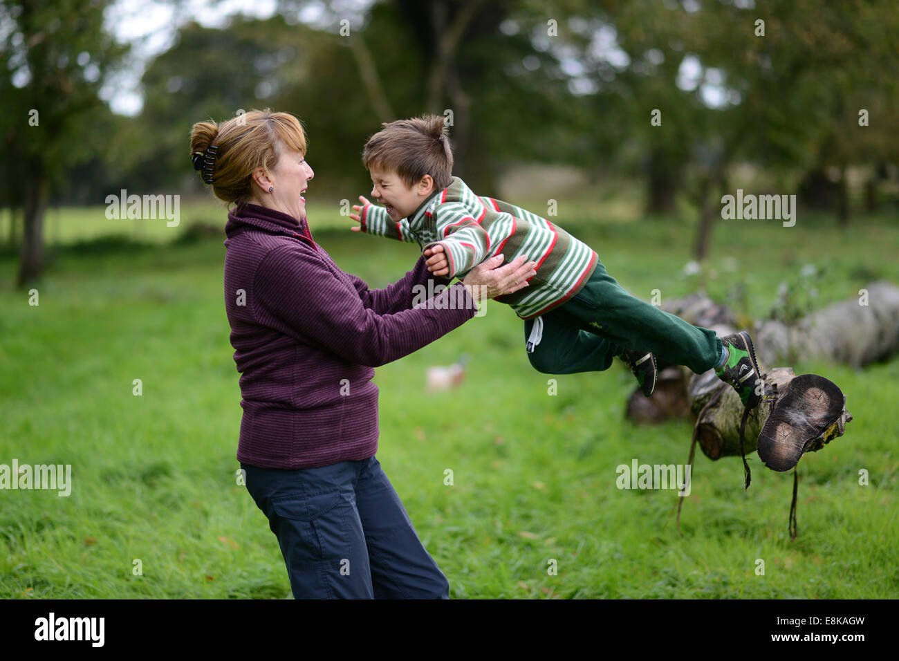 Kind Kinder junge Outdoor-Spaß mit Oma in die Arme springen trust vertrauensvolle Uk Stockfoto