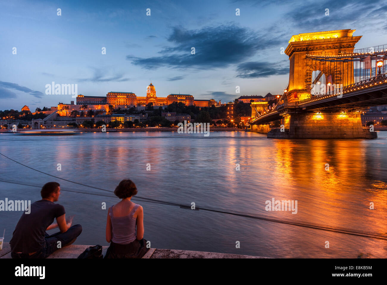 Junges Paar am Ufer auf Donau, Budaer Burg und Széchenyi Kettenbrücke in der Nacht, Budapest Ungarn Stockfoto