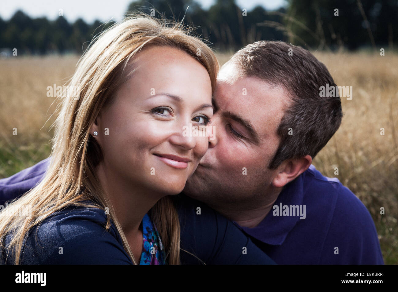 Mann küsst Freundin auf Wange Stockfoto