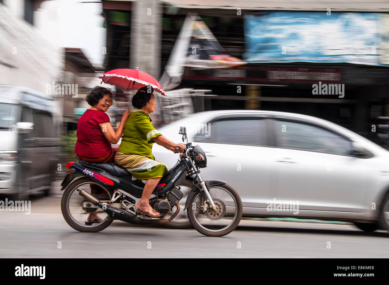 Zwei Frauen auf einem Motorrad mit roten Sonnenschirm, Chiang Mai, Nord-Thailand, Thailand Stockfoto