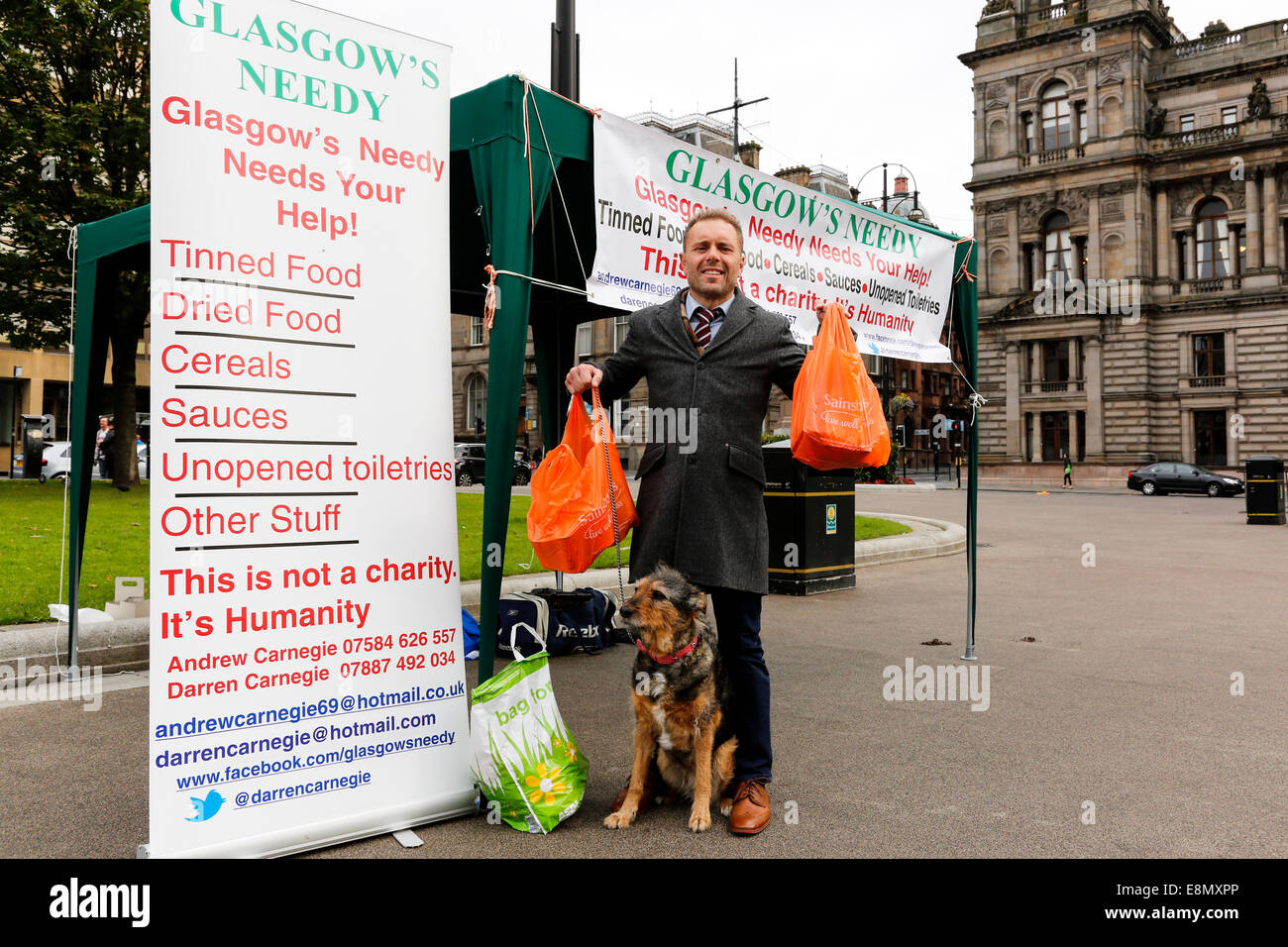 Glasgow, Schottland. 11. Oktober 2014. Andrew Carnegie, im Alter von 45 aus Tollcross in Glasgow, wer die Tafel Nächstenliebe, die einen Stall in der George Square, das Stadtzentrum von Glasgow außerhalb der City Chambers mit der Absicht, Beiträge zu sammeln und auch Aufmerksamkeit auf soziale Ungleichheit und die Bedürfnisse der Armen 'Glasgows Needy' einrichten einrichten. Mehrere Passanten - mit dazu beigetragen, seine Liebe durch Abgabe Taschen von Lebensmitteln, einschließlich Colin Boyd, im Alter von 38 Firmenchef von Kilwinning.  Bildnachweis: Findlay/Alamy Live-Nachrichten Stockfoto